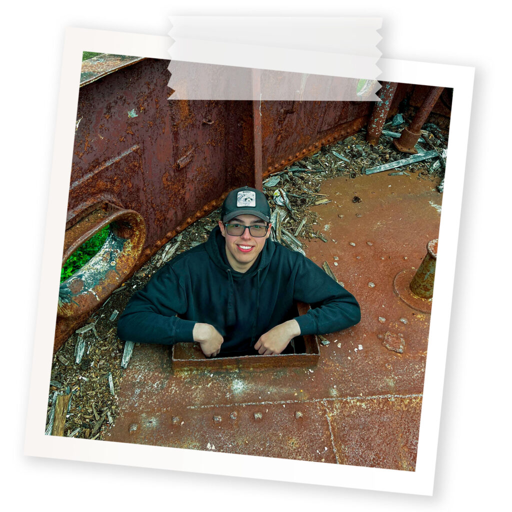 A polaroid of a student inside an abandoned boat in the forest.